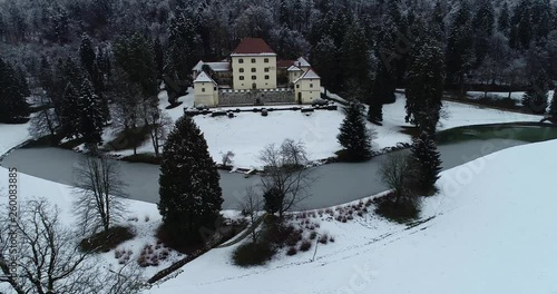 Backwards moving drone aerial view of an old castle and a landscape covered in snow, on a cold winter day. photo