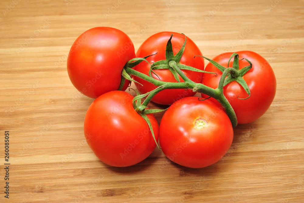 Five Fresh Tomatoes Over a Wooden Background Five Fresh Tomatoes Over a Wooden Background