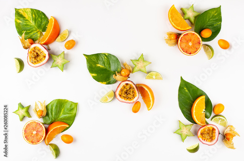 Colorful pattern of whole and sliced exotic fruits with tropical leaves and flowers