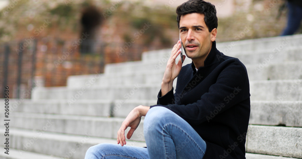 Young man talking on the phone sitting on stairs outdoor Young man talking on the phone sitting on stairs outdoor