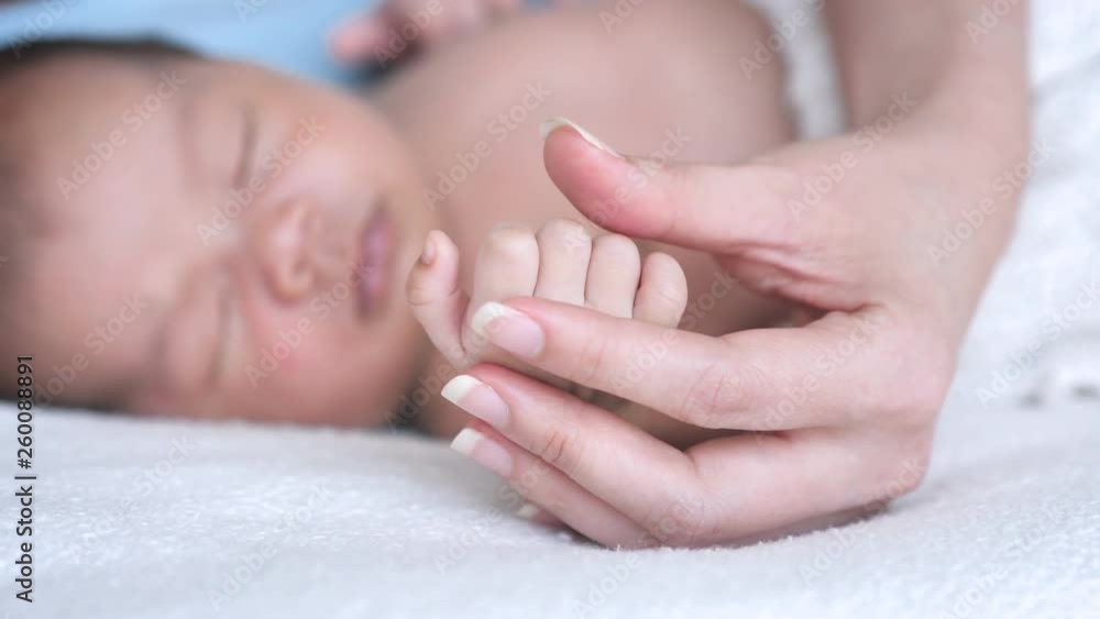 Close up Mother holding hands Asian female newborn baby and sunlight in the morning. Cute little girl three weeks old. Healthcare, love, relationship concept Close up Mother holding hands Asian female newborn baby and sunlight in the morning. Cute little girl three weeks old. Healthcare, love, relationship concept