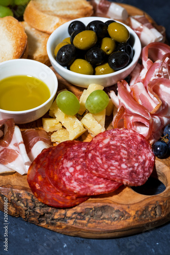 cold cuts, bread and cheese on wooden board, vertical