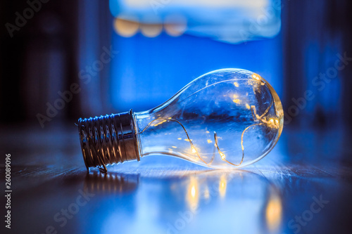 Ideas and innovation: Light bulb with LEDs is lying on the wooden floor. Window and light in the blurry background.
