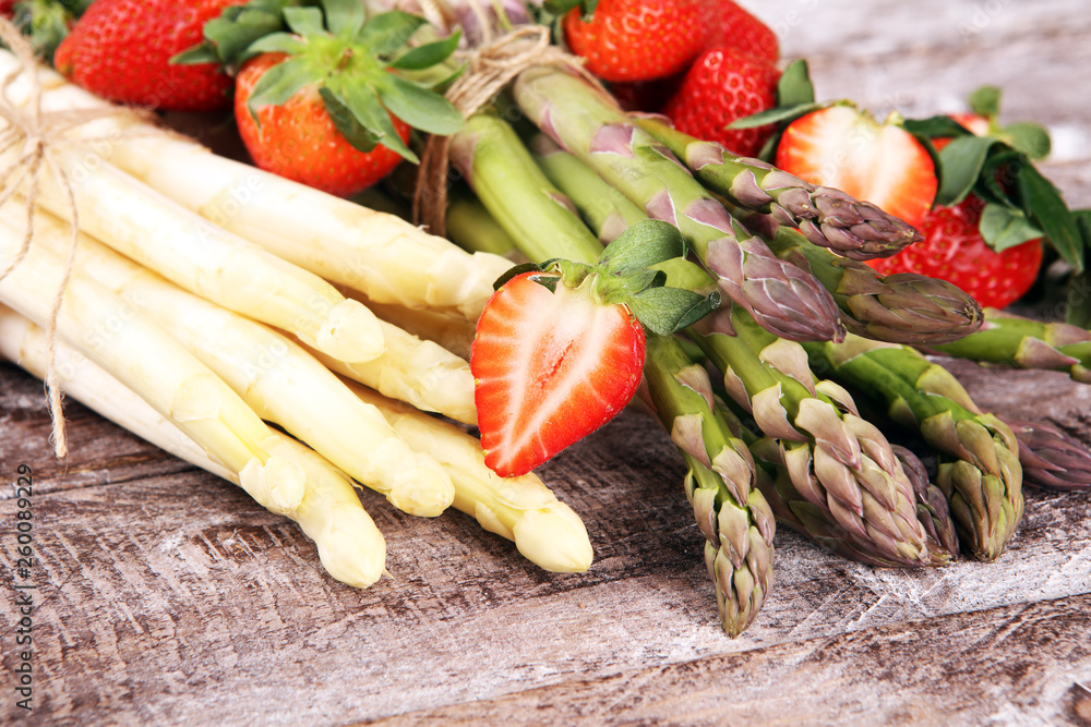 White and green asparagus with strawberries on wood White and green asparagus with strawberries on wood