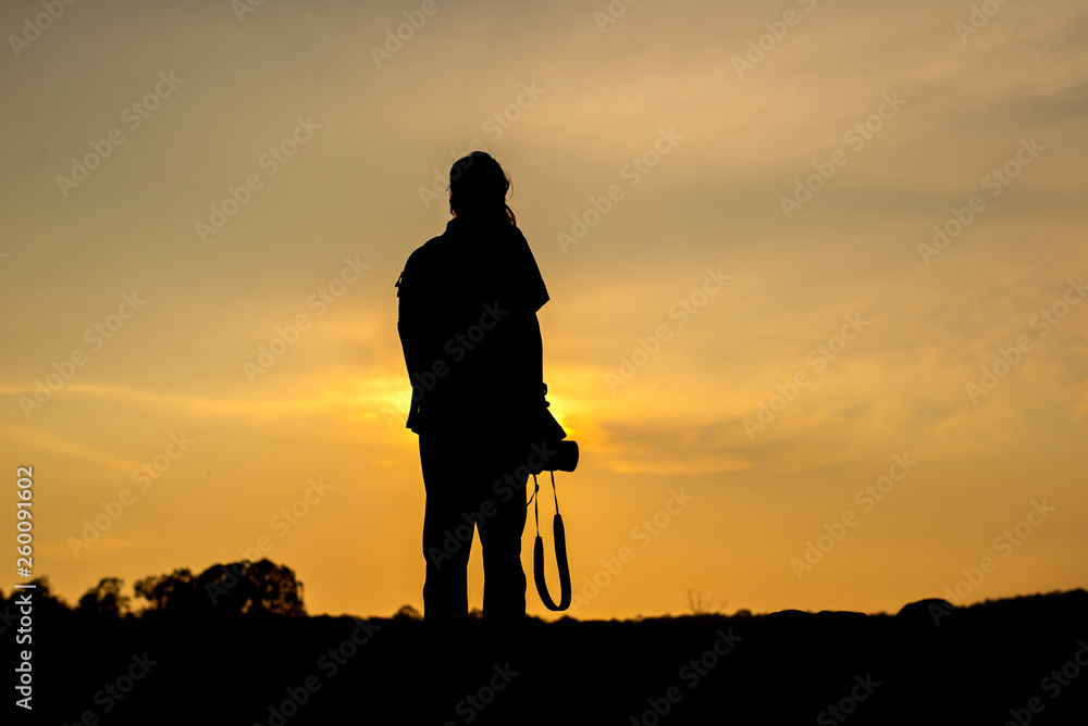 Silhouette sunset with person holding camera