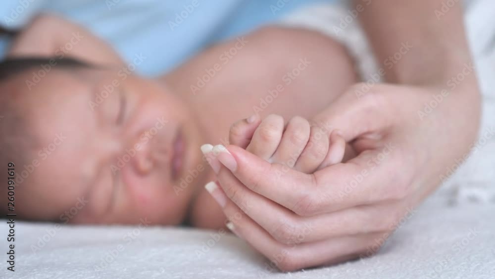 Close up Mother holding hands Asian female newborn baby and sunlight in the morning. Cute little girl three weeks old. Healthcare, love, relationship concept Close up Mother holding hands Asian female newborn baby and sunlight in the morning. Cute little girl three weeks old. Healthcare, love, relationship concept