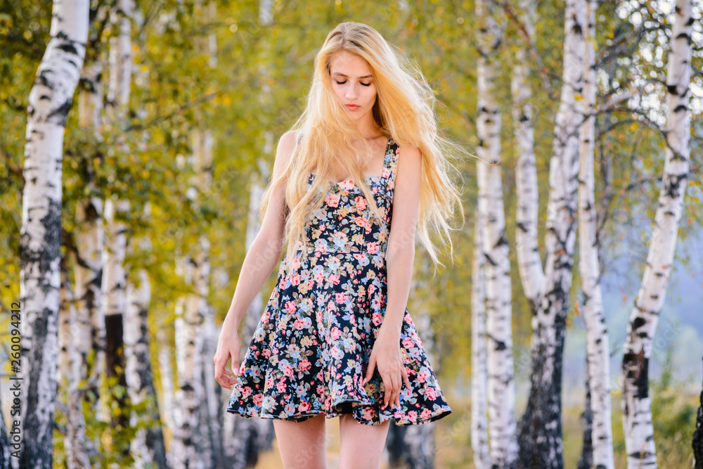An attractive girl with long hair in a short dress walks in the Park. An attractive girl with long hair in a short dress walks in the Park.