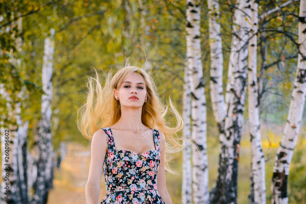 An attractive girl with fluttering hair and a short dress walks in the Park.