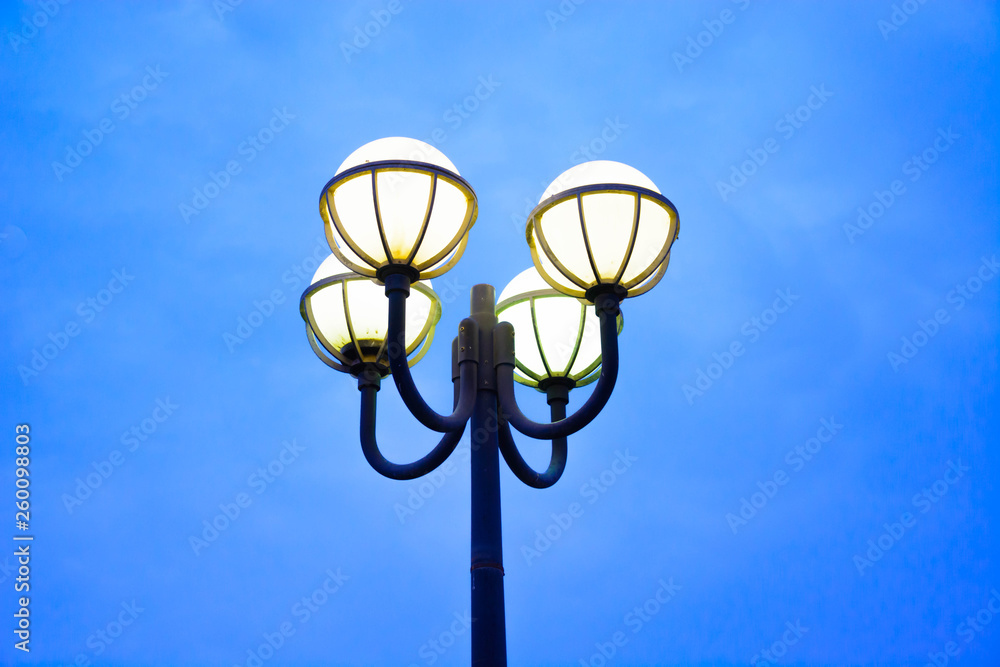 Modern yellow street light bulbs on lamp post with blue sky background on evening Modern yellow street light bulbs on lamp post with blue sky background on evening