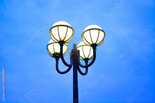 Modern yellow street light bulbs on lamp post with blue sky background on evening