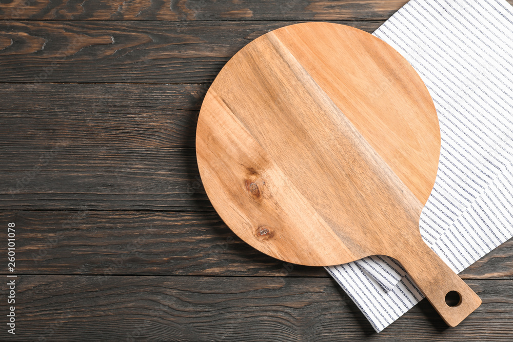 Cutting board with kitchen towel on wooden background, space for text Cutting board with kitchen towel on wooden background, space for text