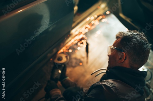 man in goggles for cutting metal, stpli with an electric rotating angle grinder and works by generating metallic sparks. construction industryм