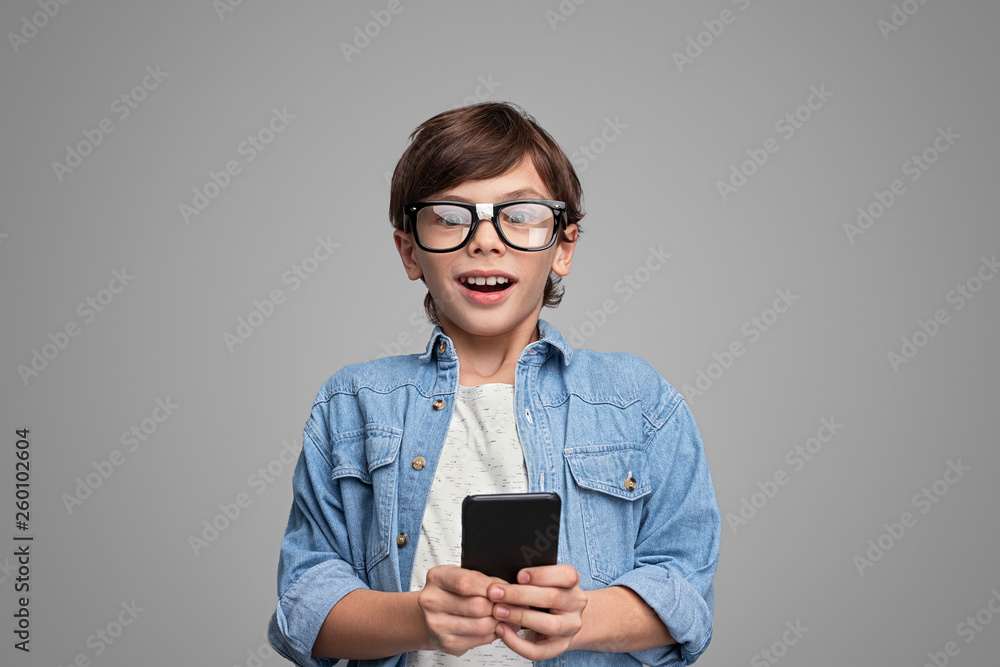 Excited boy with smartphone looking at camera Excited boy with smartphone looking at camera