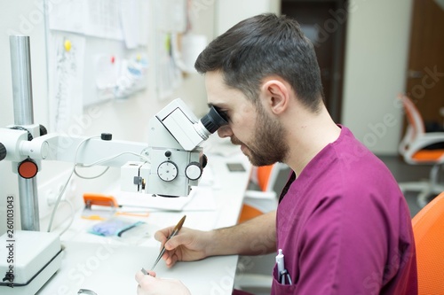 young male researcher studying a biological sample in a microscope