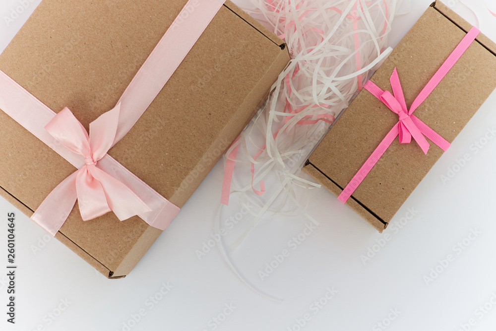 Kraft gift boxes with pink bow on white background and copy space - obrazy, fototapety, plakaty 
