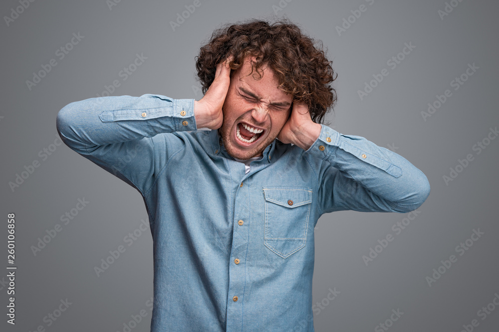 Man screaming and covering ears