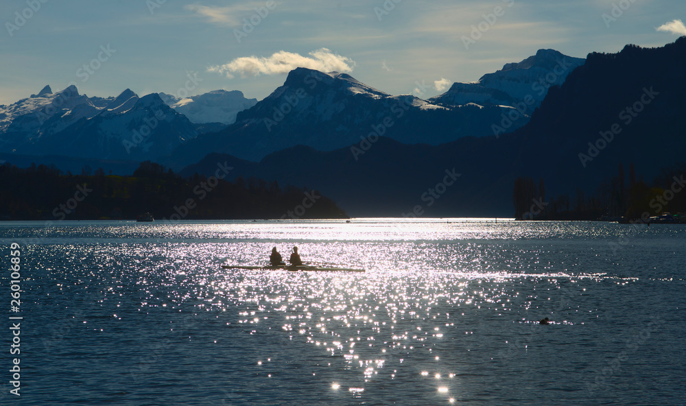 A lone skiff against the light before mountain range 