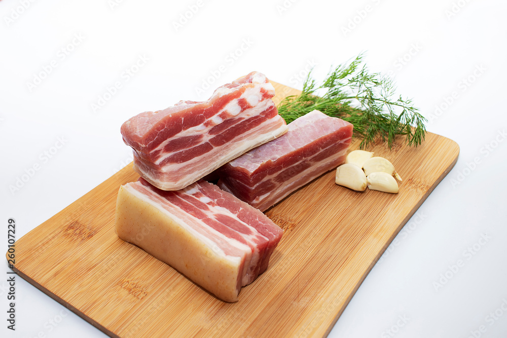 Slices of pork belly with garlic and herbs on a cutting board. Juicy slices of meat with bacon with pepper and garlic. Slices of pork belly with garlic and herbs on a cutting board. Juicy slices of meat with bacon with pepper and garlic.