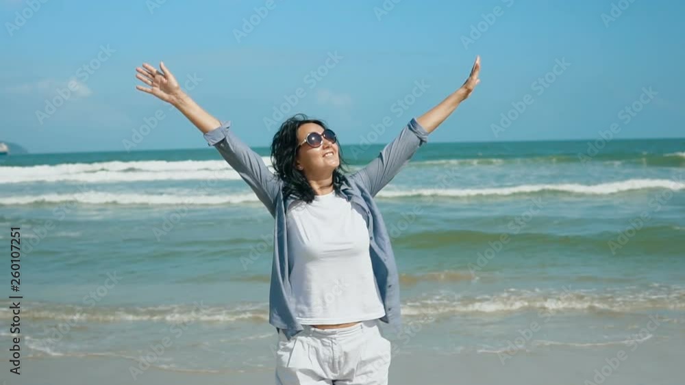 Portrait of attractive smiling woman raising hands on a tropical beach on sunny day. Slow motion people footage. Handheld camera. Portrait of attractive smiling woman raising hands on a tropical beach on sunny day. Slow motion people footage. Handheld camera.