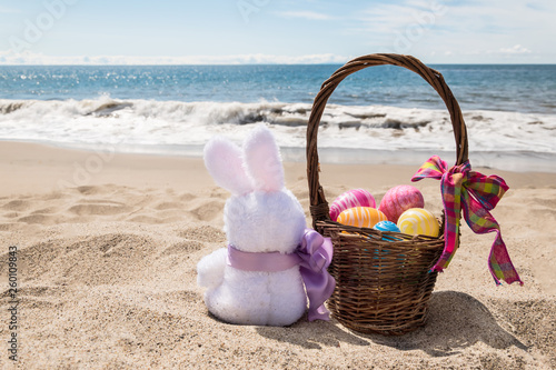 Easter bunny with color eggs on the ocean beach