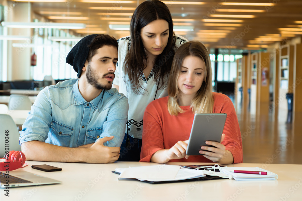 University students using digital tablet in university library. University students using digital tablet in university library.