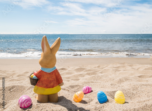 Easter bunny with color eggs on the ocean beach