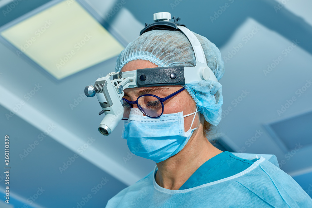 Close up portrait of female surgeon doctor wearing protective mask and hat during the operation. Healthcare, medical education, surgery concept. Close up portrait of female surgeon doctor wearing protective mask and hat during the operation. Healthcare, medical education, surgery concept.