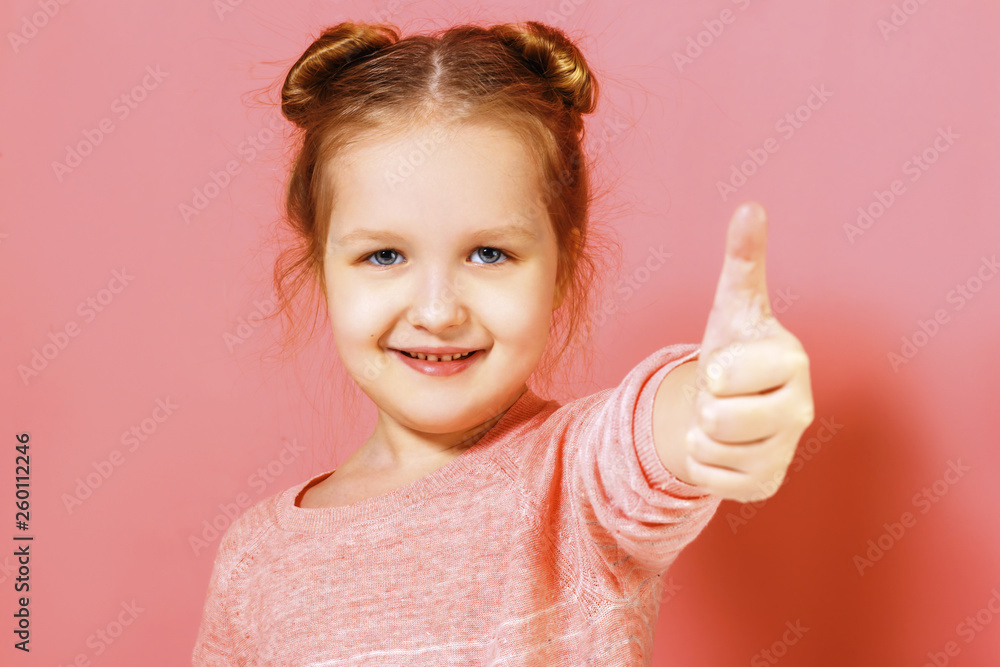 Closeup portrait of a cute attractive little child girl showing thumb up over pink background. Closeup portrait of a cute attractive little child girl showing thumb up over pink background.