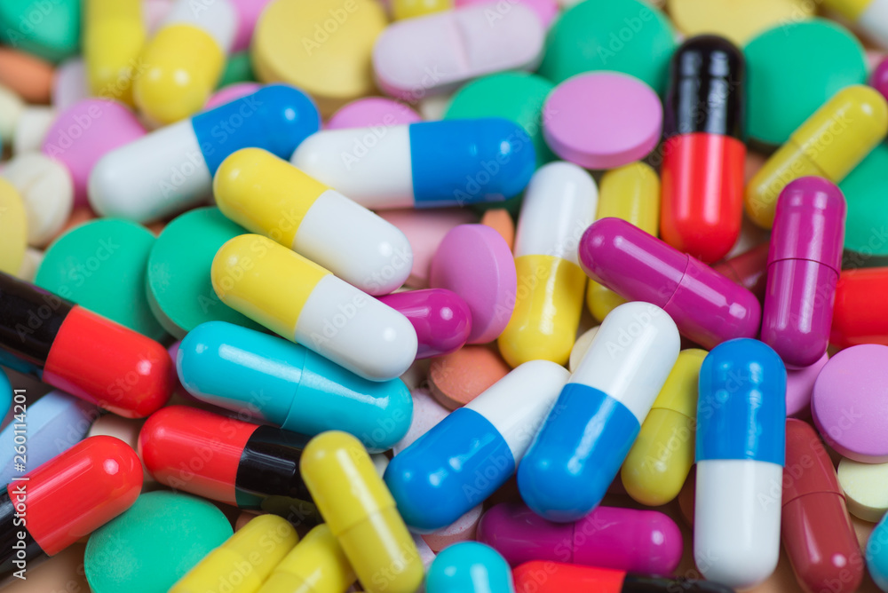 Medicine green, yellow, red and pink pills or capsules on a blue background Medicine green, yellow, red and pink pills or capsules on a blue background