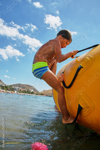 Boy playing on water trampoline on the sea at sunny day © Georgii