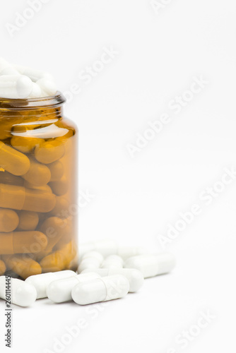 Medicine white pills or tablets drop out of the brown glass bottle on white background.