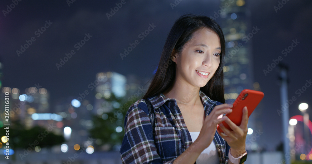 Woman use mobile phone online in the city at night Woman use mobile phone online in the city at night
