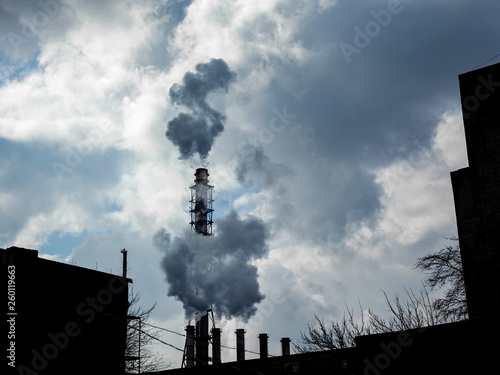 Industrial pipes smoke and release white smoke into the sky with clouds. Air pollution and harmful emissions from poor ecology of the environment and global warming. photo