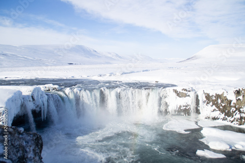 Scenic landscape view of tourist popular attraction Godafoss waterfall in northern Iceland in winter time. Long exposure falling water photo, snow covered mountains on background. 