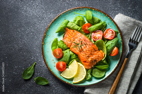 Baked salmon fish fillet with fresh salad top view.