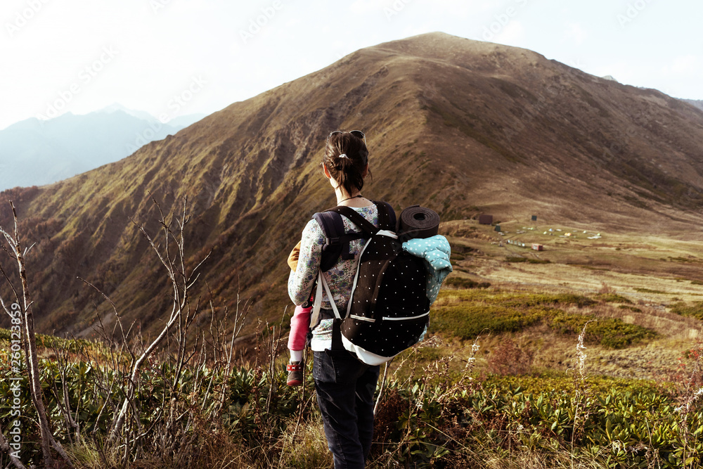 woman with a backpack in the mountains is a rear view