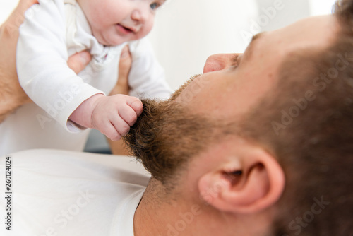 Baby infant hands grab beard of man