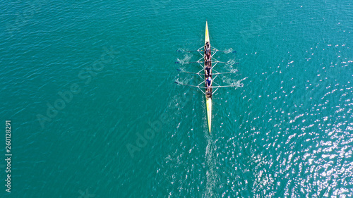 Aerial drone bird's eye view photo of yellow sport canoe operated by team of young team in emerald clear sea