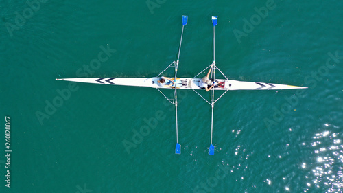 Aerial drone bird's eye view of sport canoe operated by 2 young women in turquoise clear waters