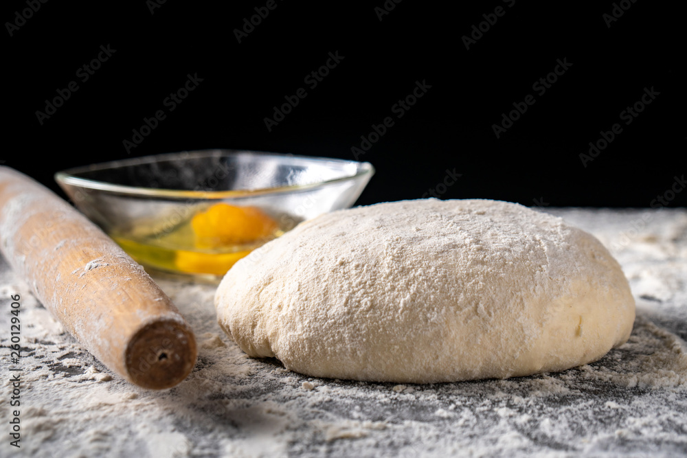 White flour with eggs, butter and dough on a cooking board White flour with eggs, butter and dough on a cooking board