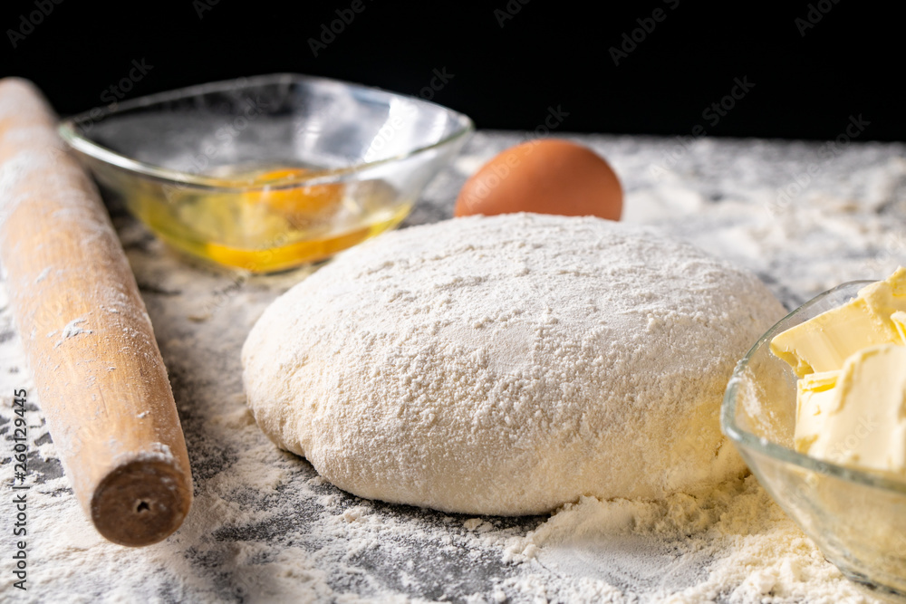 White flour with eggs, butter and dough on a cooking board White flour with eggs, butter and dough on a cooking board