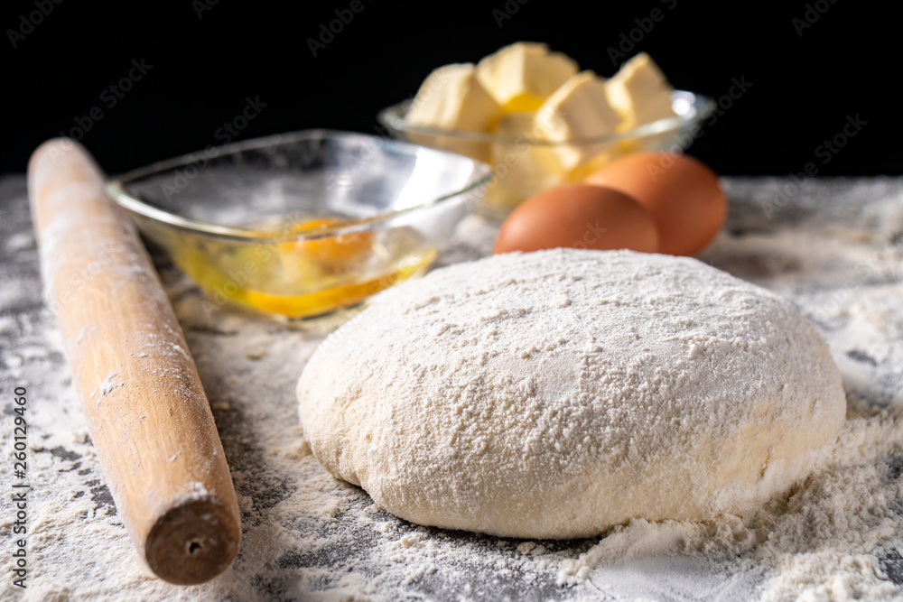 White flour with eggs, butter and dough on a cooking board