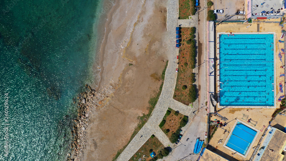 Aerial drone top view photo of turquoise swimming pool located next to the sea