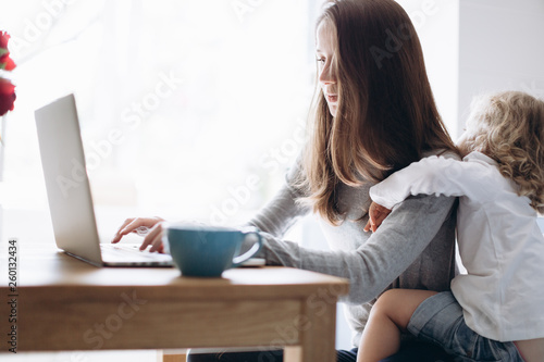 Young mother and her little daughter sitting using a laptop