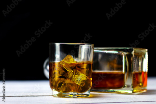 Glass with whiskey and ice cubes on multicolored rainbow background. Part of set.
