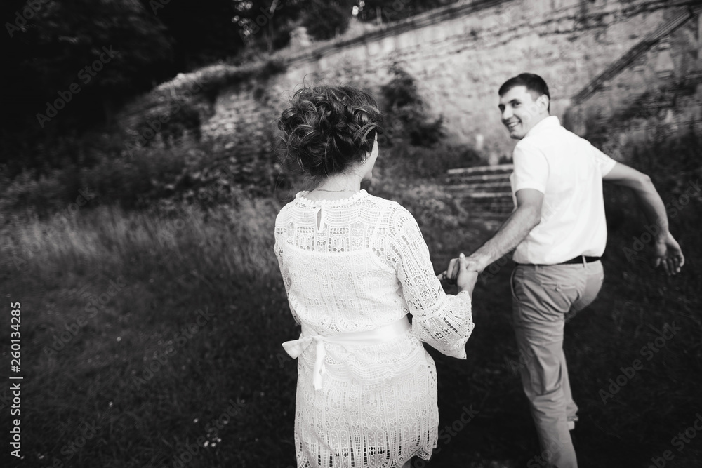 A wonderful love story. Young couple walking around the old wall of castle. Black and white