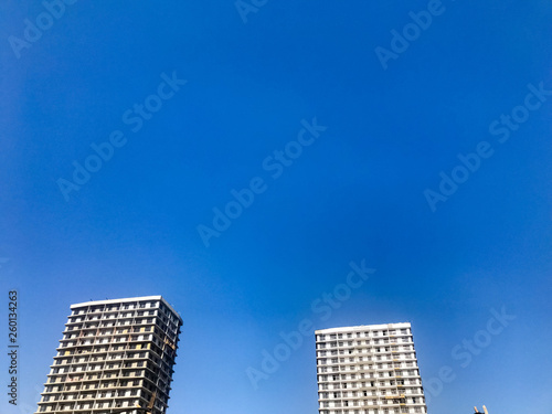 Two large high reinforced concrete  panel  monolithic-frame  frame-block houses  buildings  skyscrapers  new buildings with a glare of the sun in the windows against the blue sky