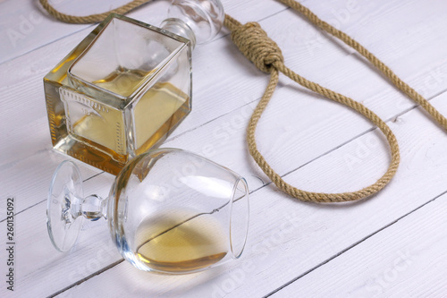 Rope with a loop, decanter and glass with alcohol on white wooden background. Hopelessness concept.