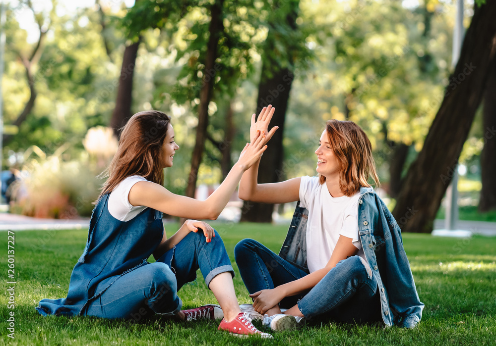 Happy female friends raising hands up giving high five in city park Happy female friends raising hands up giving high five in city park