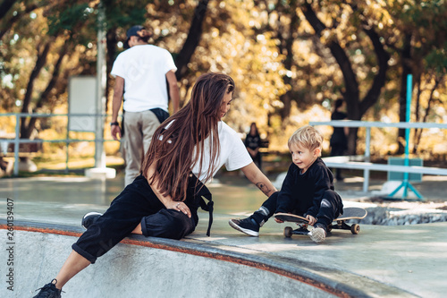 Beautiful young hipster mom and little son at the skatepark